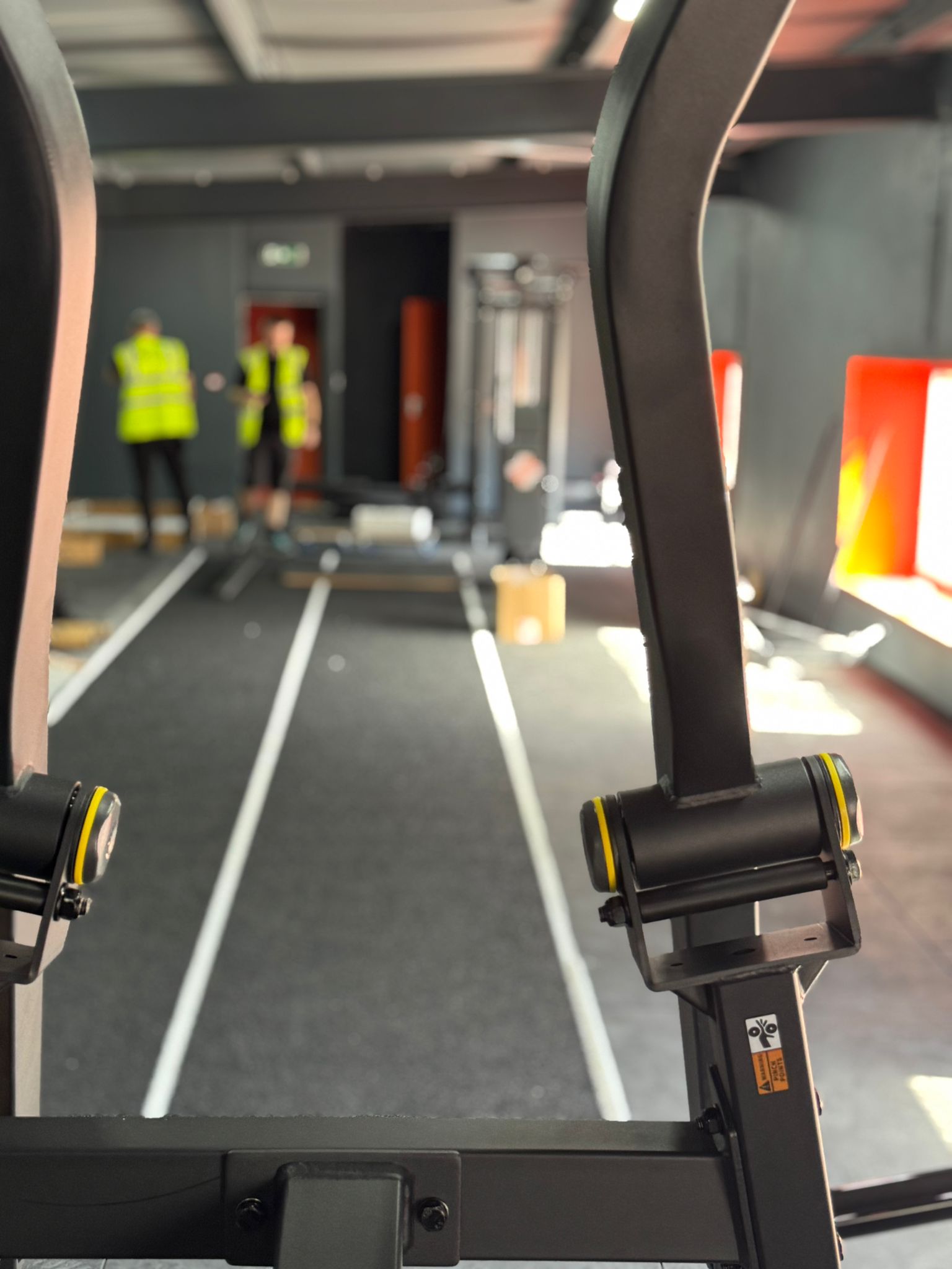 Installers in hi-vis vests fitting gym equipment